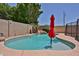 Inviting backyard pool with rock features, lush greenery, and stylish red umbrella at 21141 N 79Th Ave, Peoria, AZ 85382