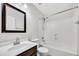 Bright bathroom features a vanity with dark wood cabinets, a framed mirror, and a shower over tub at 23075 W Arrow Dr, Buckeye, AZ 85326