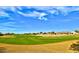 Beautiful lush green golf course on a sunny day with blue skies and beautiful homes in the background at 23075 W Arrow Dr, Buckeye, AZ 85326