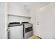 Bright laundry room with modern washer and dryer, convenient shelving, and tile flooring at 23075 W Arrow Dr, Buckeye, AZ 85326