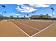 Well maintained tennis court with lighting and surrounded by a tall fence on a sunny day at 23075 W Arrow Dr, Buckeye, AZ 85326