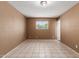 View of an empty bedroom with light tiled floors and a window overlooking the green outdoors at 233 E 7Th Dr, Mesa, AZ 85210