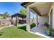 Spacious backyard featuring a covered patio, artificial grass, desert landscaping, and pergola with a seating area at 31332 N 137Th Ln, Peoria, AZ 85383