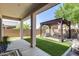 Outdoor living area showcasing a covered patio, artificial grass, desert landscaping, and a pergola with seating at 31332 N 137Th Ln, Peoria, AZ 85383