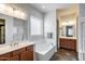 Bright bathroom featuring a soaking tub, double sink vanity, and walk-in closet at 31332 N 137Th Ln, Peoria, AZ 85383