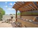 Inviting outdoor kitchen with a built-in BBQ, bar, and wooden pergola with lattice detail at 32826 N 54Th St, Cave Creek, AZ 85331