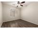 Well-lit bedroom with wooden flooring, ceiling fan and large window with blinds at 36538 W La Paz St, Maricopa, AZ 85138
