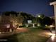 Relaxing backyard oasis with outdoor fireplace, hot tub, and lush landscaping at night at 4442 E Fairbrook St, Mesa, AZ 85205