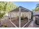 Backyard showcasing a large screened enclosure, ideal for plants, with gravel, brick accents, and an AC unit at 4928 E Paradise Ln, Scottsdale, AZ 85254