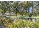 Backyard view overlooking a lush greenbelt area with a white fence, mature trees, and flowering bushes at 4928 E Paradise Ln, Scottsdale, AZ 85254