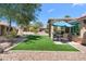 Artificial grass backyard area with covered patio and desert landscaping at 5024 S Citrus Ct, Gilbert, AZ 85298