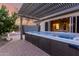 A covered hot tub with elegant water features sits on a brick patio next to a fire pit and an open sliding glass door at 5607 W Alyssa Ln, Phoenix, AZ 85083