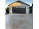 Detached garage with a modern black door and stylish sconce lighting, and a concrete driveway at 753 W 6Th Dr, Mesa, AZ 85210