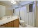 This bathroom features a single sink vanity, white toilet, shower-tub combination with a curtain and neutral color scheme at 8769 W Washington St, Tolleson, AZ 85353