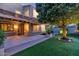 Inviting backyard features a covered patio, artificial turf, and mature tree illuminated by landscape lighting at 9582 W Albert Ln, Peoria, AZ 85382
