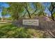 Stone community sign for The Villages at Crismon Creek surrounded by lush green lawns and mature shade trees at 10062 E Isleta Ave, Mesa, AZ 85209