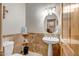 Comfortable bathroom with pedestal sink, tiled accent wall, toilet, vanity lighting, and rustic wooden door at 1032 E Dolores Rd, Phoenix, AZ 85086