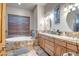 Bright bathroom with a soaking tub, dual vanities, tile floor, and a window for natural light at 1032 E Dolores Rd, Phoenix, AZ 85086