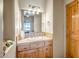 Cozy bathroom vanity featuring stone countertop, wooden cabinets, vanity lighting, and decorative mirror at 1032 E Dolores Rd, Phoenix, AZ 85086
