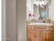 Bathroom vanity featuring stone countertop, wooden cabinets, vanity lighting, and decorative mirror at 1032 E Dolores Rd, Phoenix, AZ 85086