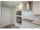 Modern kitchen with stainless steel appliances, white cabinetry and tile backsplash at 11133 W Cameo Dr, Sun City, AZ 85351