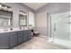 Bathroom featuring a double vanity, framed mirrors, and a glass-enclosed shower with marble accents at 11622 W Palm Brook Dr, Avondale, AZ 85392