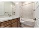 Well-lit bathroom with a wood vanity, quartz countertops, and a shower-tub with neutral colored tile at 13619 W Hackamore Dr, Peoria, AZ 85383