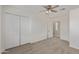 Cozy bedroom featuring a ceiling fan, double closet and neutral colored walls and carpet at 17471 W Watson Ln, Surprise, AZ 85388