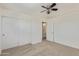 Comfortable bedroom with ceiling fan, closet, and neutral colored walls and carpet at 17471 W Watson Ln, Surprise, AZ 85388