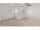 This bedroom has neutral carpet, two windows, and a ceiling fan with light fixture at 17471 W Watson Ln, Surprise, AZ 85388