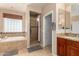 Well-lit bathroom featuring a soaking tub, walk-in shower, and a vanity with tile flooring at 19415 W Colter St, Litchfield Park, AZ 85340