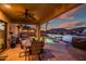 Inviting covered back patio with ceiling fan, dining table, and waterfront views with a shimmering pool at sunset at 20657 N 56Th Ave, Glendale, AZ 85308