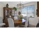 Formal dining room featuring a wood table, upholstered chairs, stylish light fixture, and built-in china cabinet at 22476 E Indiana Ave, Queen Creek, AZ 85142