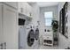 Well-lit laundry room features modern washer, dryer, storage cabinets, sink, and stylish decorations at 22476 E Indiana Ave, Queen Creek, AZ 85142