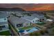Sunset aerial of the backyard oasis with a sparkling pool, patio, and mountain views in the distance at 2324 E Saguaro Park Ln, Phoenix, AZ 85024
