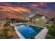 Backyard view of the sparkling pool and well-manicured landscaping as the sky turns colors at sunset at 2324 E Saguaro Park Ln, Phoenix, AZ 85024