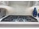 Modern stainless steel gas cooktop with white subway tile backsplash and sleek range hood at 2324 E Saguaro Park Ln, Phoenix, AZ 85024