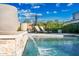 Stunning pool with a tranquil water feature, alongside lounge chairs with an umbrella, and lush landscaping at 2324 E Saguaro Park Ln, Phoenix, AZ 85024