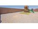 An open backyard with a play structure and a rock groundcover in a fenced lot at 29481 W Mitchell Ave, Buckeye, AZ 85396