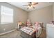 bedroom featuring a ceiling fan, large window, and a pink twin bed filled with stuffed animals at 29481 W Mitchell Ave, Buckeye, AZ 85396