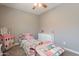 Well-lit bedroom boasts a ceiling fan, a pink twin bed filled with toys, a white dresser, and carpet floors at 29481 W Mitchell Ave, Buckeye, AZ 85396