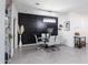 Chic dining room with a glass table, gray chairs, black accent wall, and elegant chandelier at 36076 W Santa Barbara Ave, Maricopa, AZ 85138