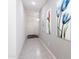 Bright hallway features modern art, clean tile floors, and access to multiple rooms with overhead lighting at 36076 W Santa Barbara Ave, Maricopa, AZ 85138