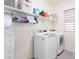 Bright laundry room with white washer and dryer, ample shelving, and a hanging rod for convenience at 36076 W Santa Barbara Ave, Maricopa, AZ 85138