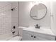 Remodeled bathroom featuring subway tile, black fixtures, and a round mirror at 3812 W Seldon Ln, Phoenix, AZ 85051