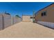 Gravel backyard with sheds, gray privacy wall, and the side of the mobile home at 3952 E Baywood Ave, Mesa, AZ 85206