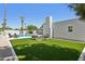 Backyard featuring a pool, artificial turf, seating, fireplace, palm trees, and exterior white brick wall at 4842 E Surrey Ave, Scottsdale, AZ 85254