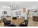 Bright dining area featuring a wooden table, black chairs, modern chandelier, and view into the kitchen at 4842 E Surrey Ave, Scottsdale, AZ 85254