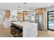 A bright kitchen features white cabinets, quartz countertops, stainless appliances, and an island with stool seating at 4842 E Surrey Ave, Scottsdale, AZ 85254
