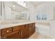 Bright bathroom with a white tub, brown cabinets, and a large mirror reflecting the glass shower at 520 E Ashurst Dr, Phoenix, AZ 85048